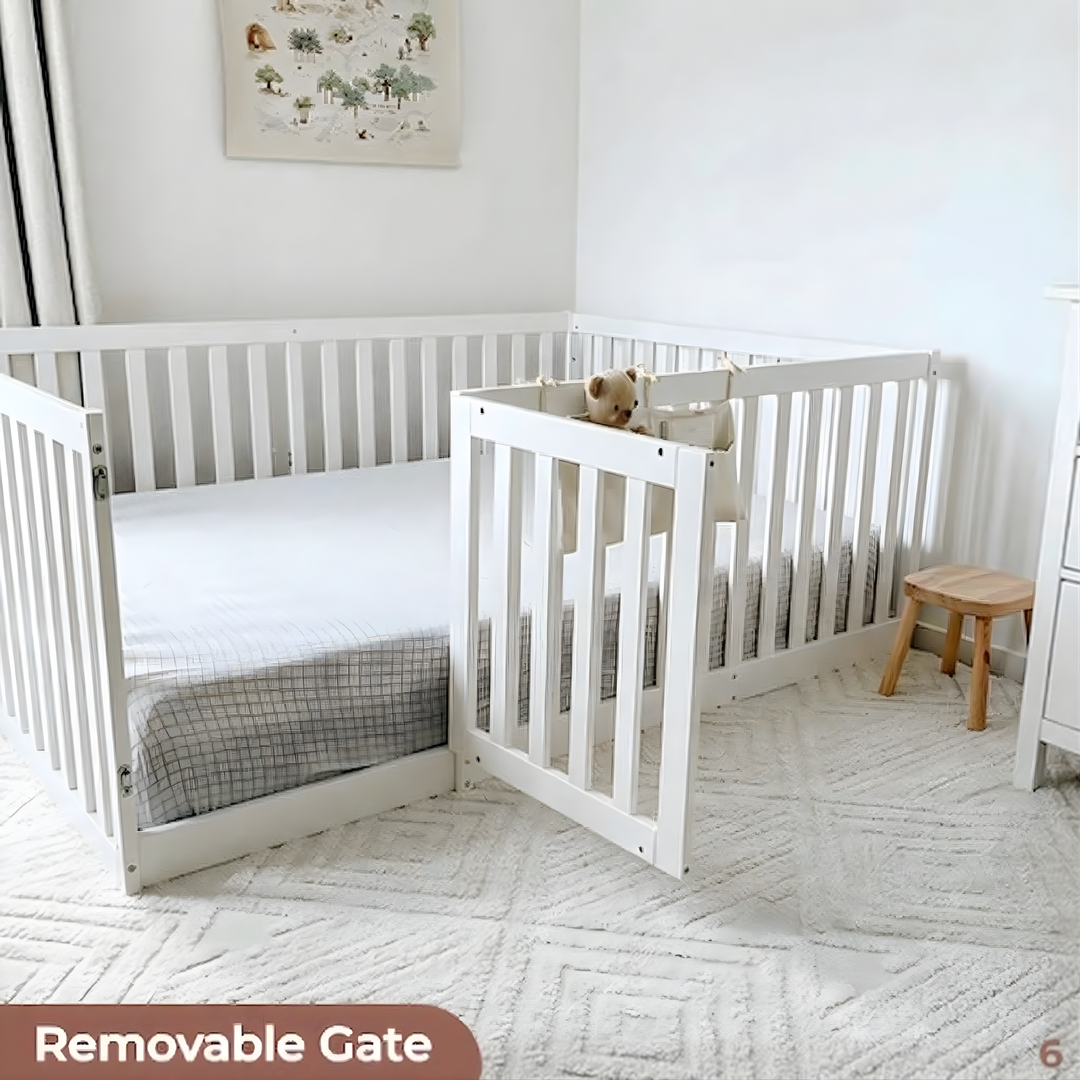 White crib with a removable gate in a nursery setting