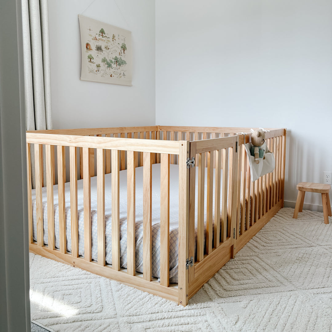 Wooden crib in a nursery with white bedding and a decorative wall hanging.
