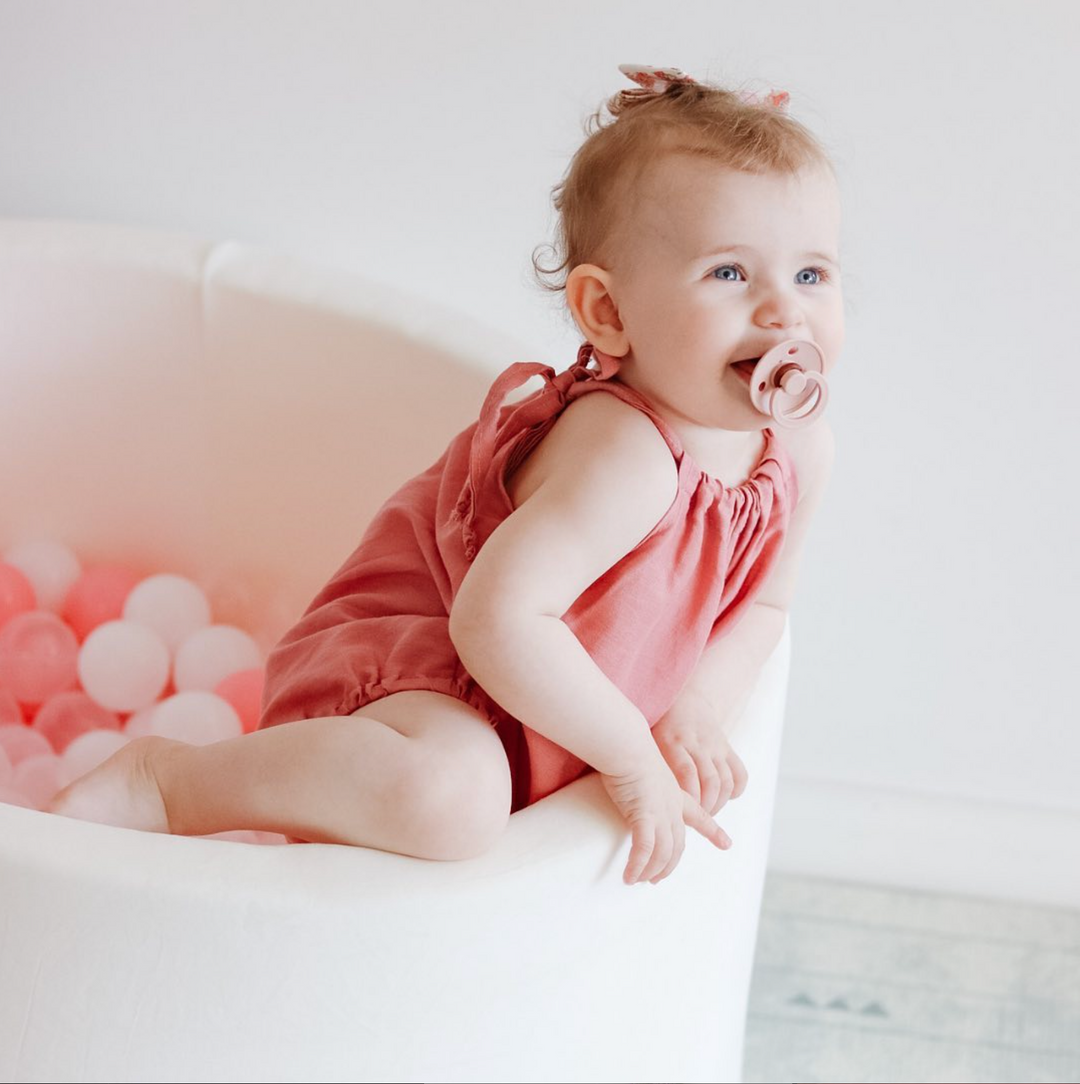 Baby Playing In A White Ball Pit