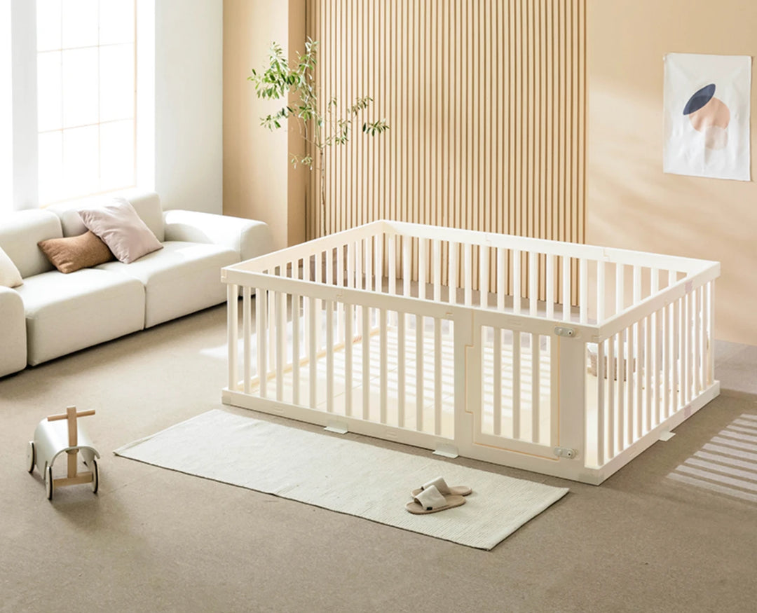 White crib in a bright, minimalistic room with a couch and decorative items.